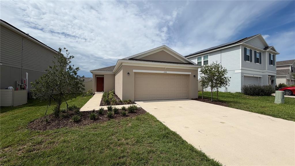 A single-story house with a beige stucco exterior, a two-car garage, and a concrete driveway — 188 BRINSMEAD ROAD, HAINES CITY, FL