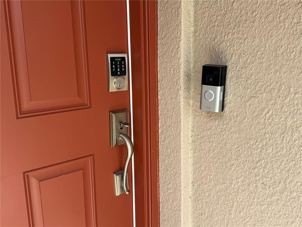 A red front door features a digital keypad lock, a handle set, and a Ring doorbell — 188 BRINSMEAD ROAD, HAINES CITY, FL