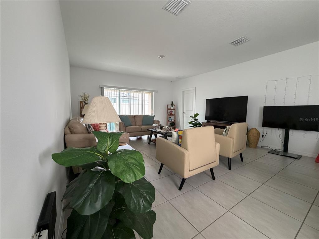 A living room features light tile flooring, neutral walls, a sofa, two armchairs, and a television — 188 BRINSMEAD ROAD, HAINES CITY, FL