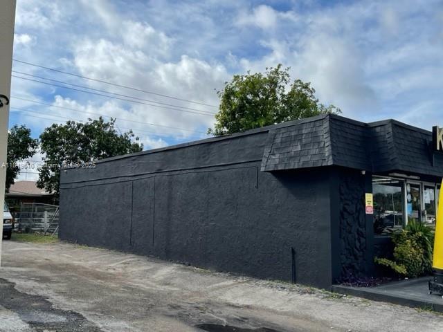 A side view of a commercial building with a black exterior and a shingled roof — 6310 Pembroke Rd, Miramar FL 33023, MIRAMAR, FL