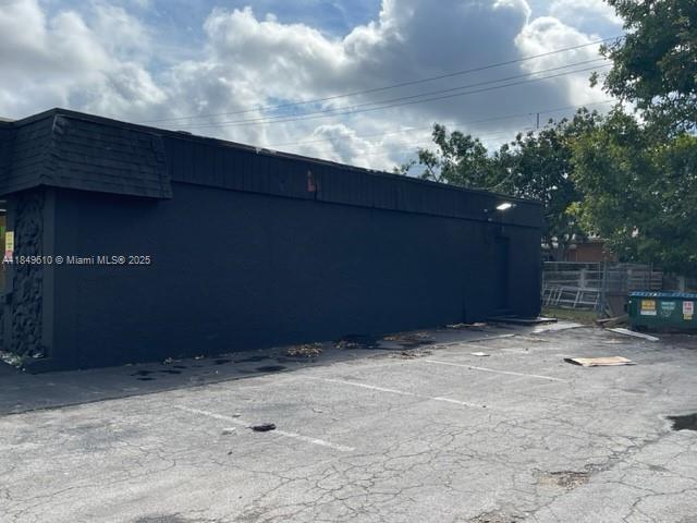 A black, windowless commercial building stands next to an asphalt parking lot under a cloudy sky — 6310 Pembroke Rd, Miramar FL 33023, MIRAMAR, FL