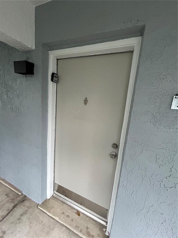 A light-colored exterior door with a metal kick plate is set in a gray wall — 109 OYSTER BAY CIRCLE UNIT 240, ALTAMONTE SPRINGS, FL