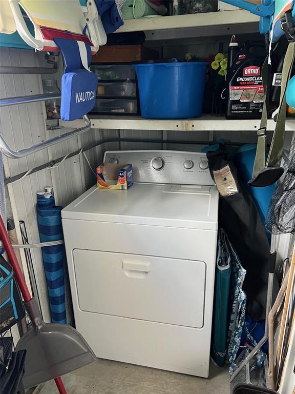 A white clothes dryer is positioned in a storage area with shelves above it — 142 FERN PALM STREET, LARGO, FL