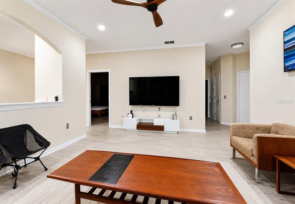 A living room features light wood flooring, a wall-mounted television, and a wooden coffee table — 15728 GREEN COVE BOULEVARD, CLERMONT, FL