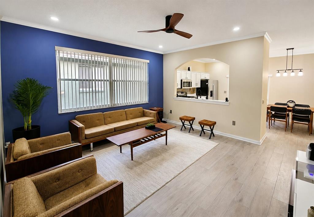 A living room with a blue accent wall, mid-century furniture, and an open kitchen view — 15728 GREEN COVE BOULEVARD, CLERMONT, FL