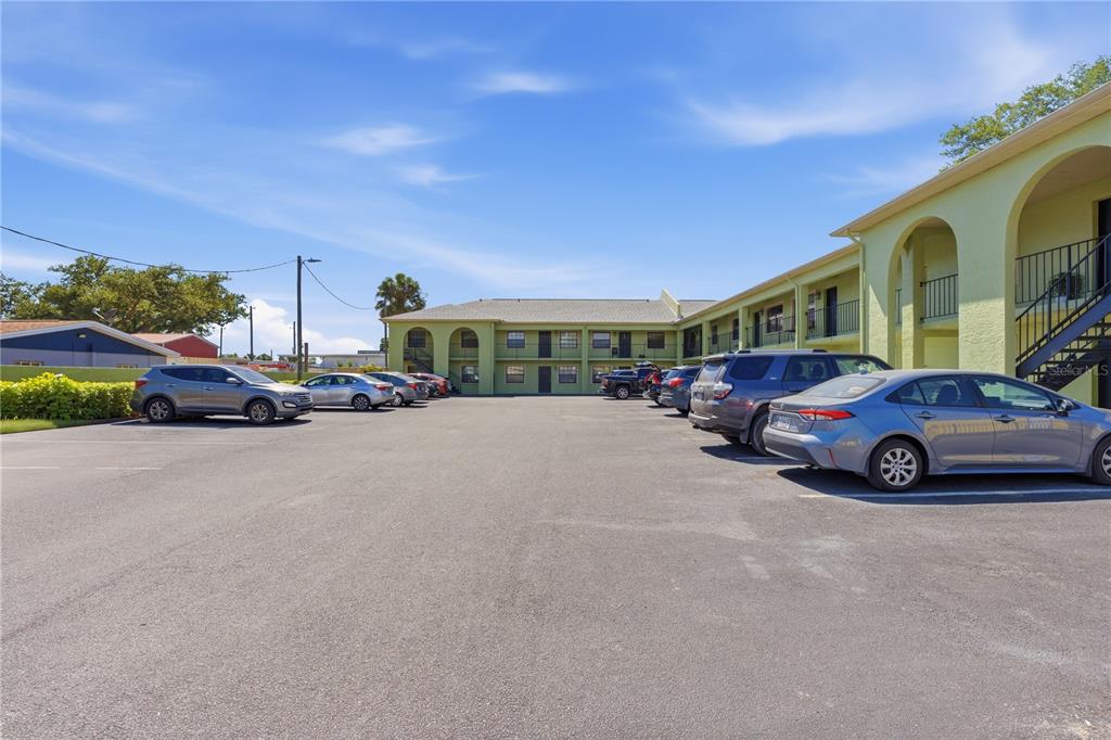 A parking lot sits in front of a two-story, light green apartment building — 4416 N CLARK AVENUE UNIT 13, TAMPA, FL