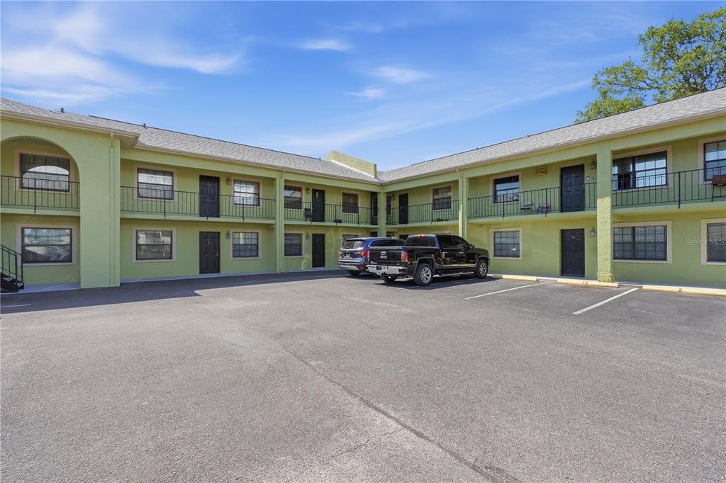A two-story, light green apartment building with an asphalt parking lot in front — 4416 N CLARK AVENUE UNIT 13, TAMPA, FL