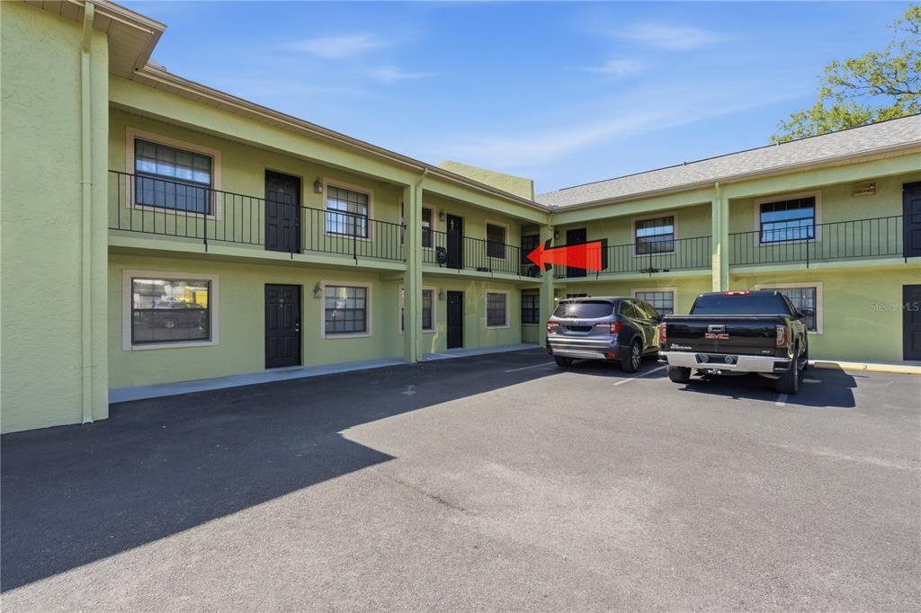A two-story apartment building with a parking lot and a red arrow pointing to a balcony — 4416 N CLARK AVENUE UNIT 13, TAMPA, FL