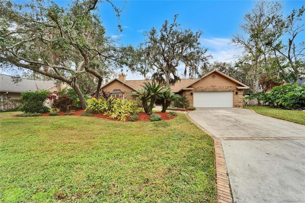 A single-story brick house with a two-car garage and mature trees in the front yard — 2913 ASTON AVENUE, PLANT CITY, FL