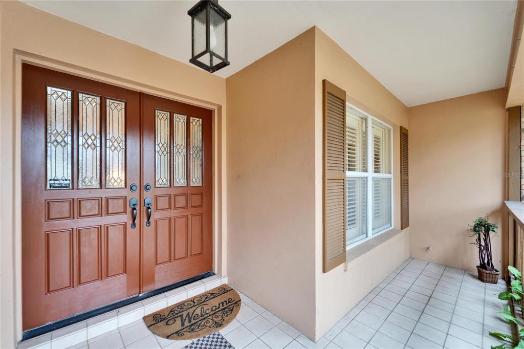 A covered porch features a double wooden front door, a welcome mat, and a window — 2913 ASTON AVENUE, PLANT CITY, FL