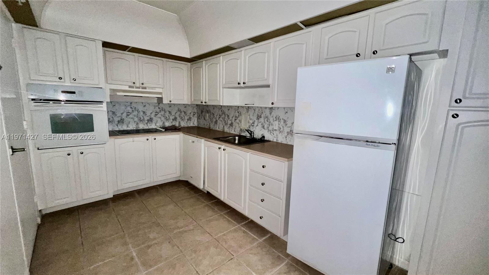 A kitchen features white cabinets, a white refrigerator, a built-in oven, and tiled flooring — 3901 S Ocean Dr # 3C, Hollywood FL 33019, HOLLYWOOD, FL