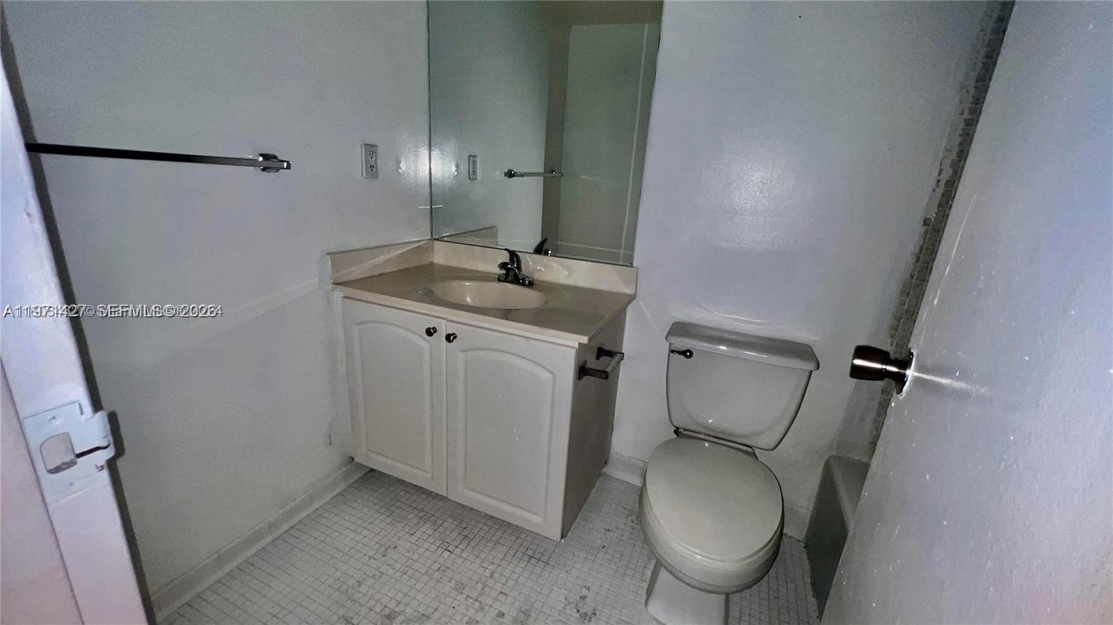 A small bathroom features a white vanity, a toilet, and a wall-mounted mirror — 3901 S Ocean Dr # 3C, Hollywood FL 33019, HOLLYWOOD, FL