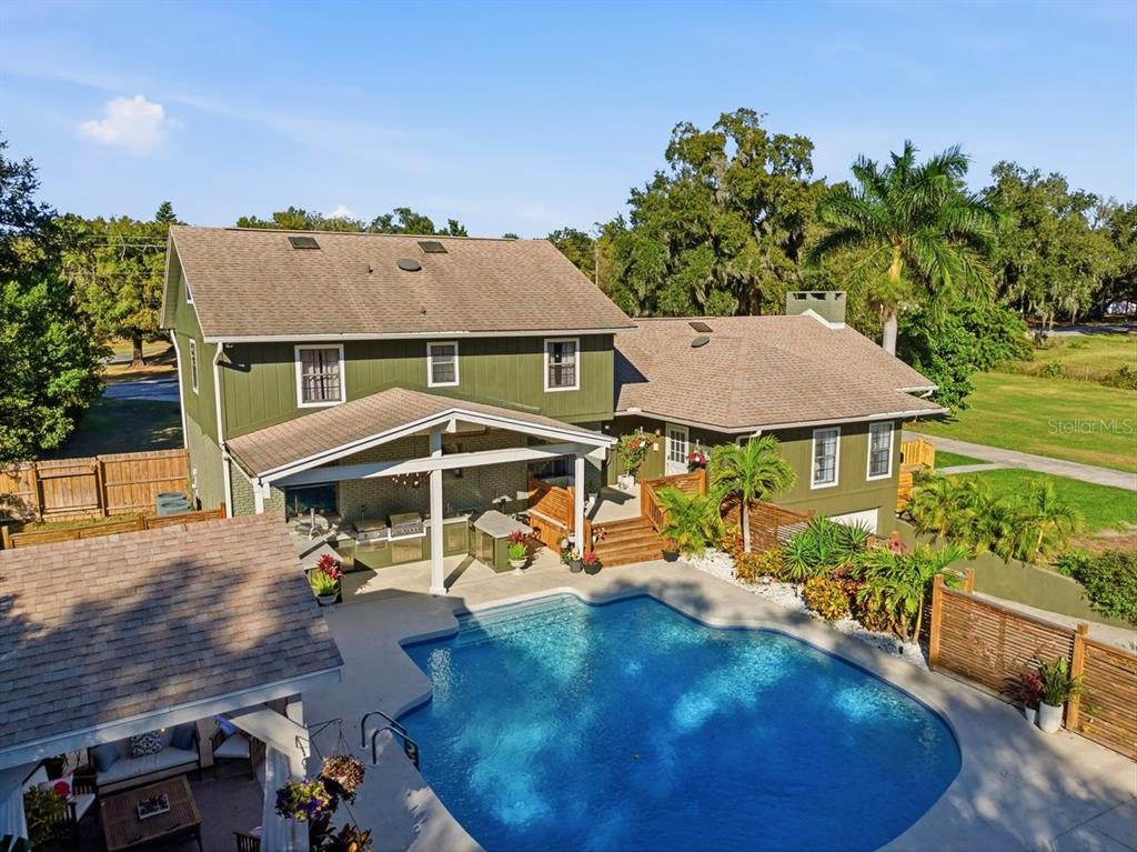 An aerial view of a two-story green house with a swimming pool and covered patio — 1825 CLUBHOUSE ROAD, LAKELAND, FL
