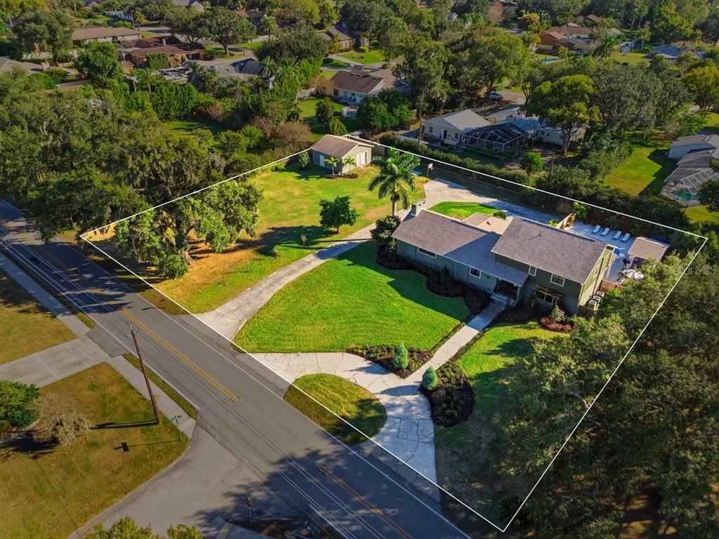 An aerial view shows a house with a pool, detached garage, and large grassy yard — 1825 CLUBHOUSE ROAD, LAKELAND, FL