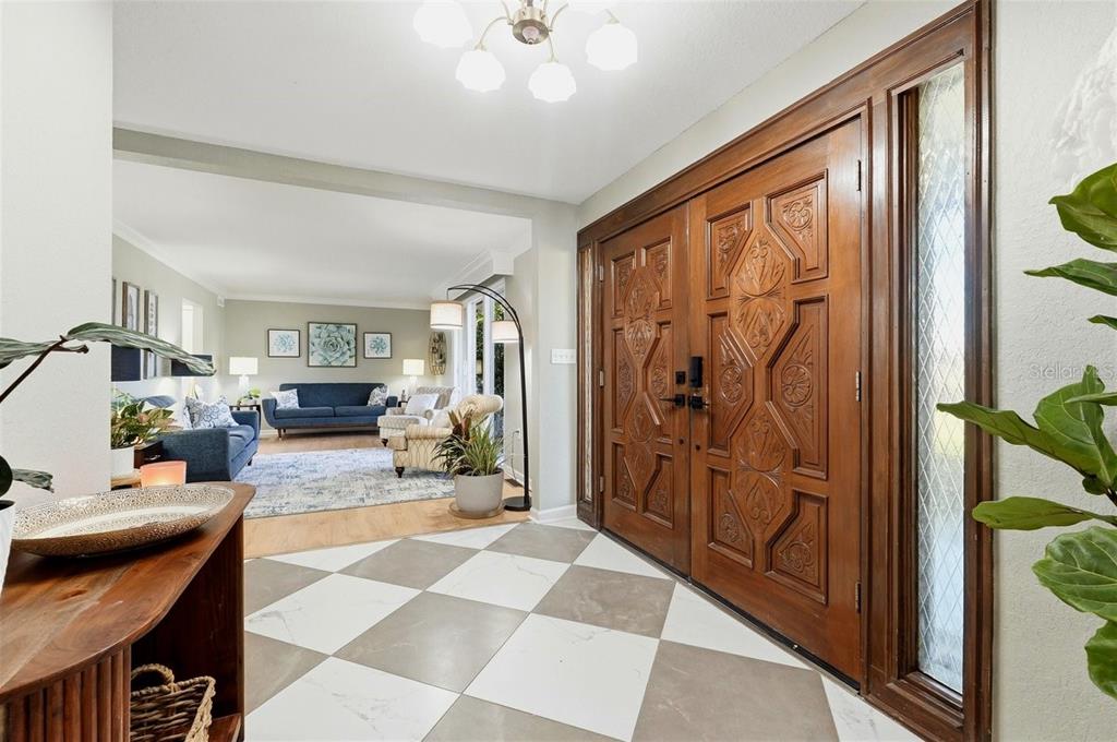 An entryway with a checkered tile floor and ornate wooden double doors leads into a living room — 1825 CLUBHOUSE ROAD, LAKELAND, FL