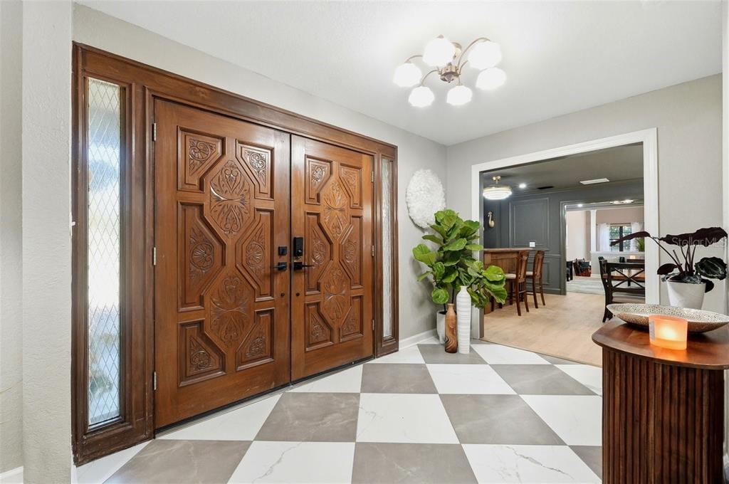 An entryway features double wood doors, a checkered tile floor, and a view into a room — 1825 CLUBHOUSE ROAD, LAKELAND, FL