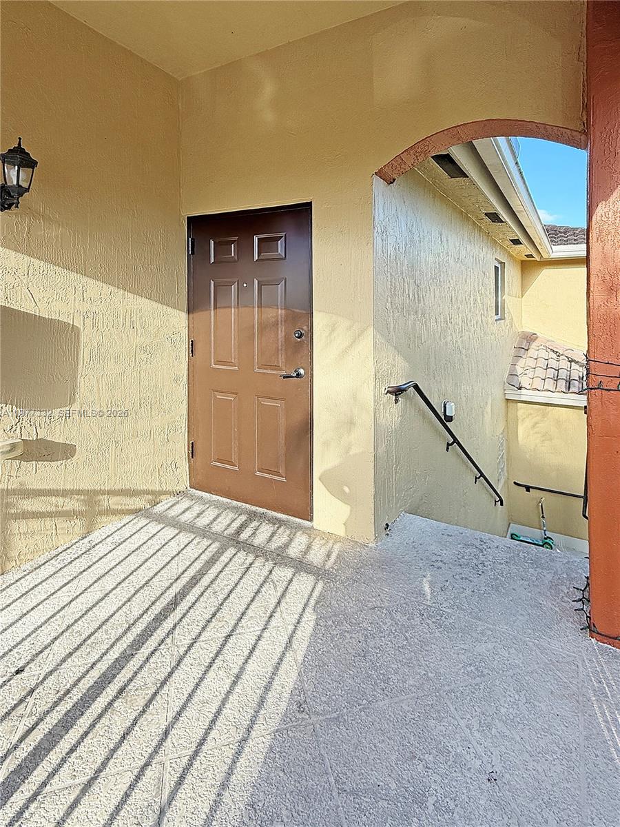 A brown door opens onto a concrete landing with a staircase leading downward — 945 NE 34th Ave # 204, Homestead FL 33033, HOMESTEAD, FL