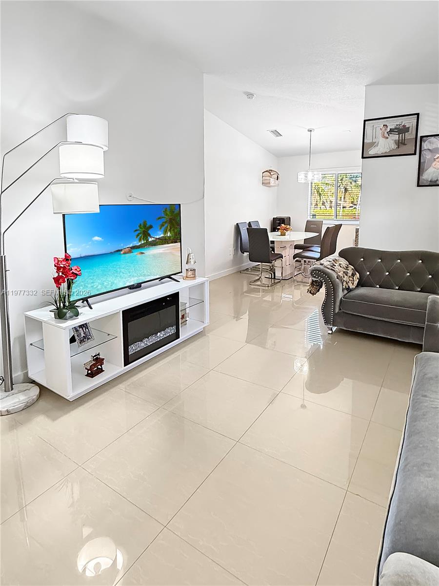 A living room features a white media console with an electric fireplace and tile flooring — 945 NE 34th Ave # 204, Homestead FL 33033, HOMESTEAD, FL