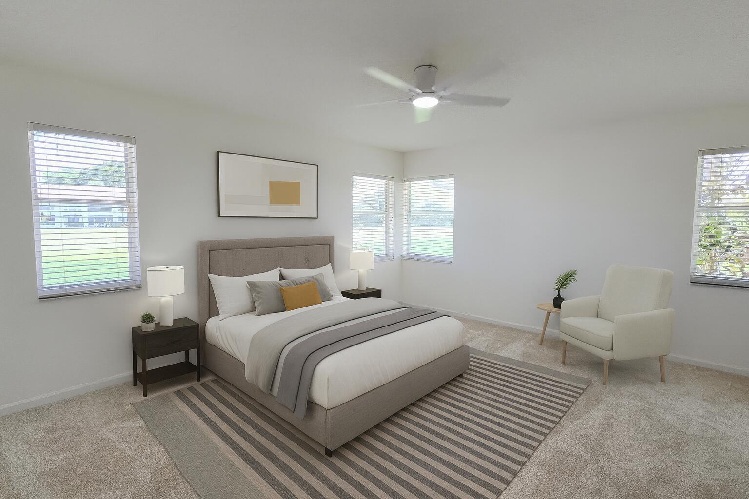 A bedroom with a bed, two nightstands, an armchair, and a striped area rug — 5622 Royal Lake Circle, Boynton Beach FL 33437, BOYNTON BEACH, FL
