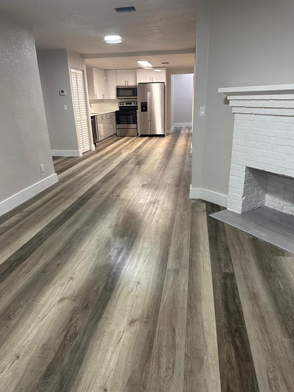 An open-concept living area with wood-look flooring leads to a kitchen with stainless steel appliances — 1150 PIPPIN STREET, JACKSONVILLE, FL