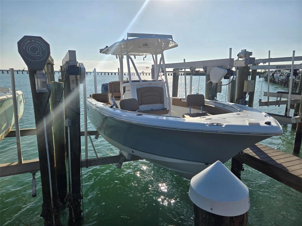 A center console boat is suspended on a lift above the water at a dock — 6040 BOCA GRANDE CAUSEWAY UNIT 03 Boat Slip, BOCA GRANDE, FL