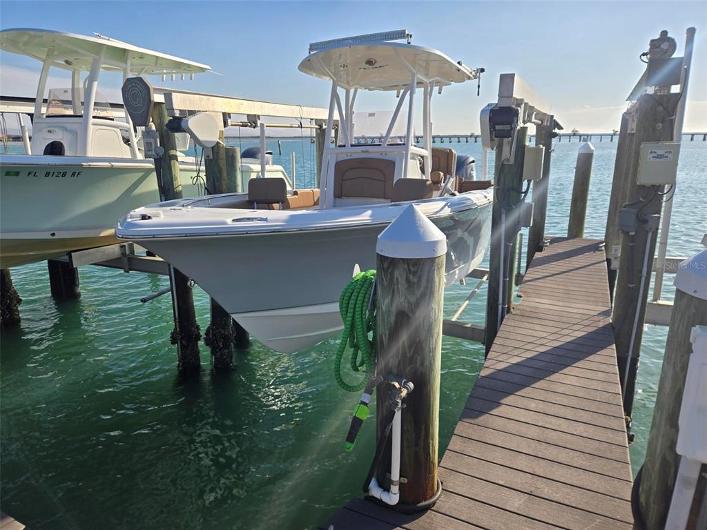 A white center console boat is suspended on a lift beside a wooden dock — 6040 BOCA GRANDE CAUSEWAY UNIT 03 Boat Slip, BOCA GRANDE, FL