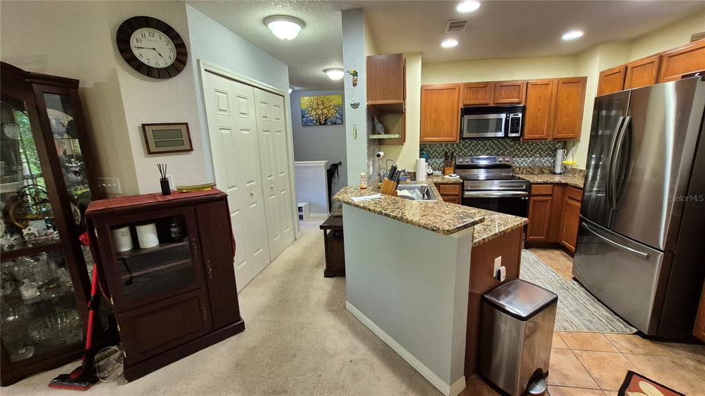 A kitchen with granite countertops, wooden cabinets, and stainless steel appliances opens to a dining area — 4600 E MOODY BOULEVARD UNIT 8M, BUNNELL, FL