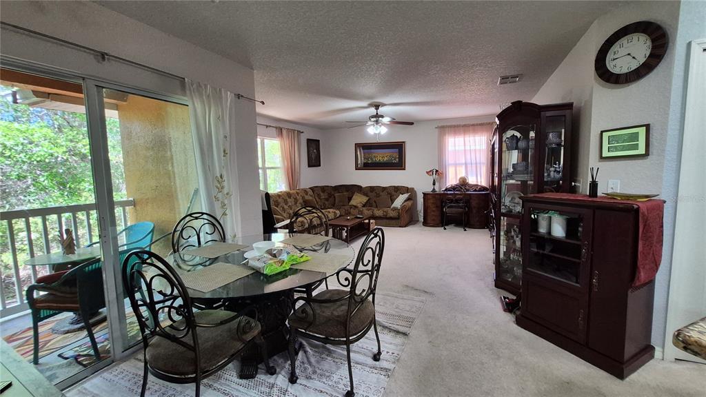 A dining area with a glass table and chairs opens into a carpeted living room — 4600 E MOODY BOULEVARD UNIT 8M, BUNNELL, FL