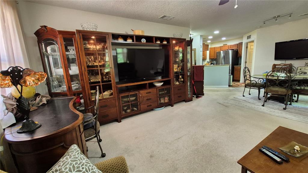A living room features a large wooden entertainment center, carpeted flooring, and an adjacent kitchen — 4600 E MOODY BOULEVARD UNIT 8M, BUNNELL, FL