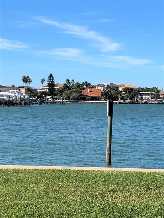 A view of a waterway with houses, palm trees, and a wooden piling in the foreground — 240 SAND KEY ESTATES DRIVE UNIT 257, CLEARWATER, FL