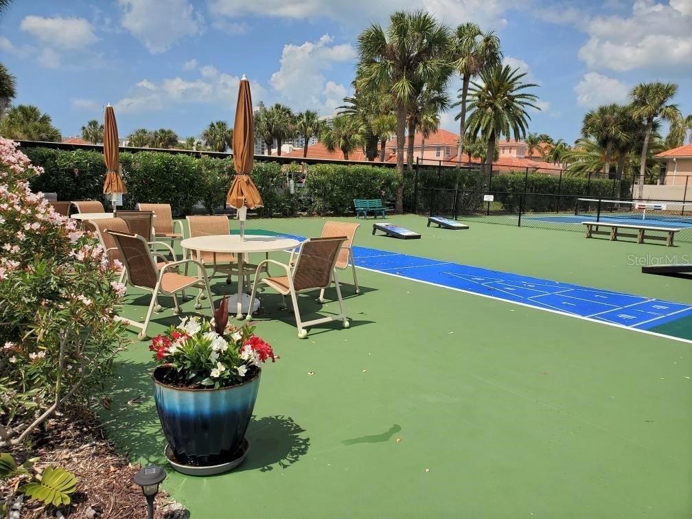 An outdoor patio area features a shuffleboard court, patio furniture, and potted flowers — 240 SAND KEY ESTATES DRIVE UNIT 257, CLEARWATER, FL