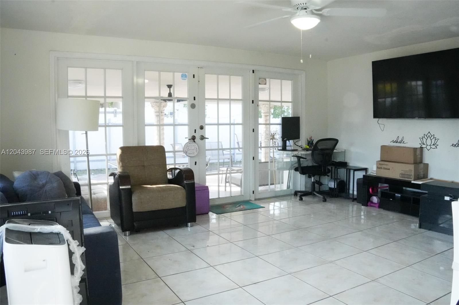 A living room features white walls, tile flooring, a ceiling fan, and glass patio doors — 2955 NW 102nd St, Miami FL 33147, MIAMI, FL