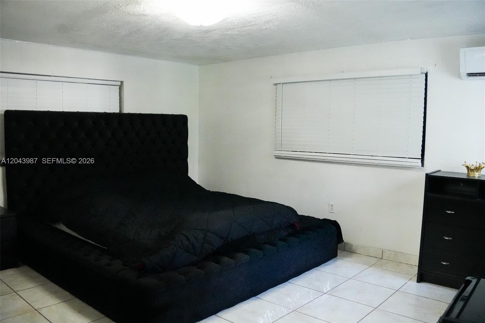 A bedroom features a large black tufted bed, white tile floors, and white walls — 2955 NW 102nd St, Miami FL 33147, MIAMI, FL