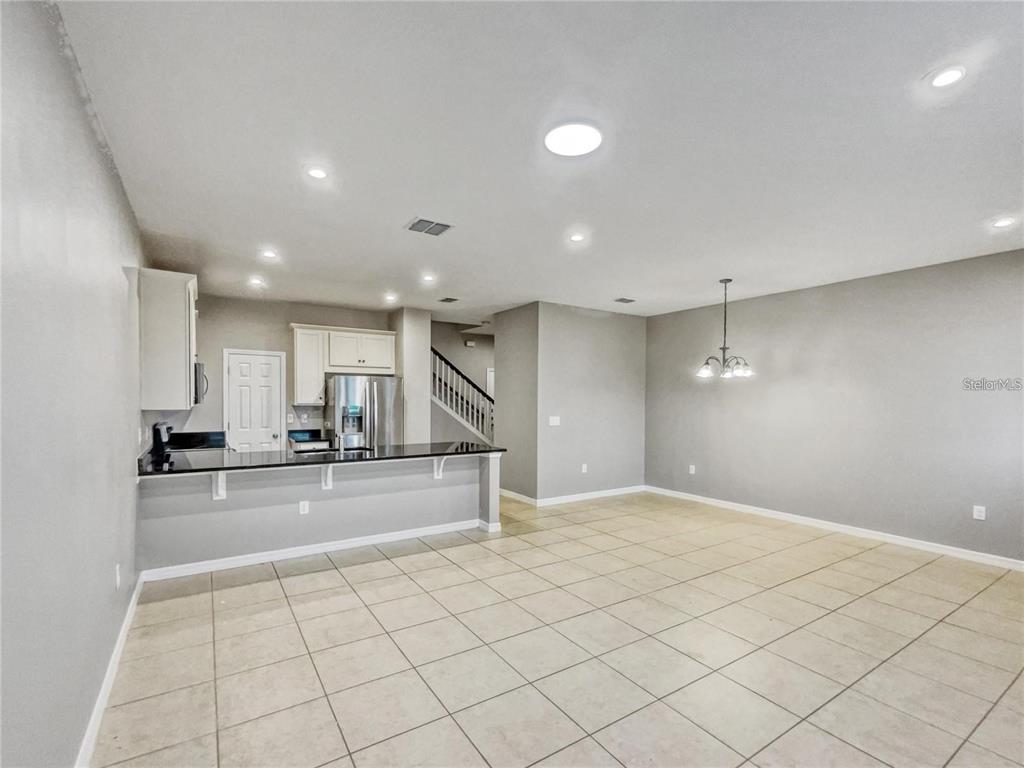 An open-concept kitchen with a breakfast bar and dining area features tile flooring throughout — 2424 BLOWING BREEZE AVENUE, KISSIMMEE, FL