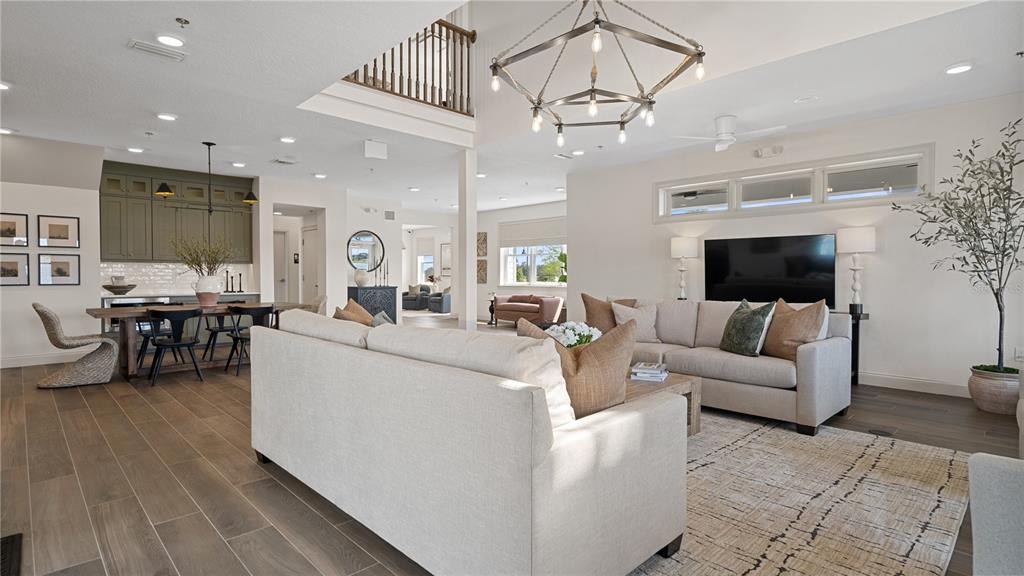 An open-concept living room features a large sectional sofa, a dining area, and high ceilings — 5550 RONIN DRIVE, ST CLOUD, FL