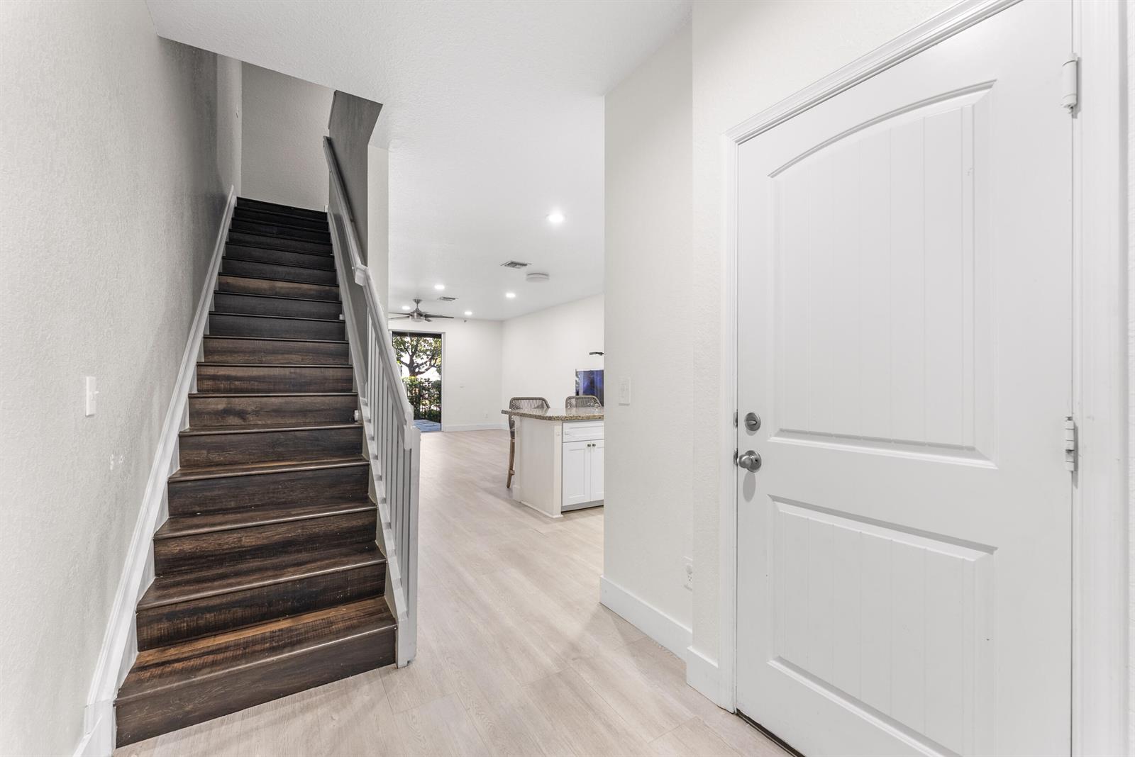 An entryway features dark wood stairs, light wood-look flooring, and a white front door — 354 SE 1st Way # 354, Deerfield Beach FL 33441, DEERFIELD BEACH, FL