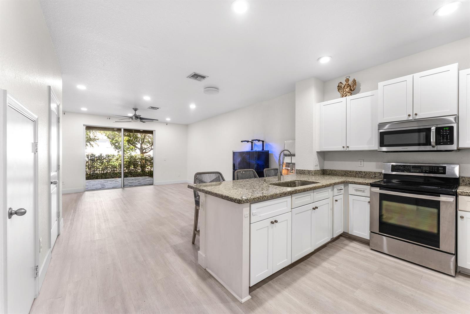 A kitchen with white cabinets and granite countertops opens into a spacious living area — 354 SE 1st Way # 354, Deerfield Beach FL 33441, DEERFIELD BEACH, FL