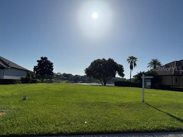 A vacant grassy lot sits between two houses under a bright sun — 906 JOHNS POINT DRIVE, OAKLAND, FL