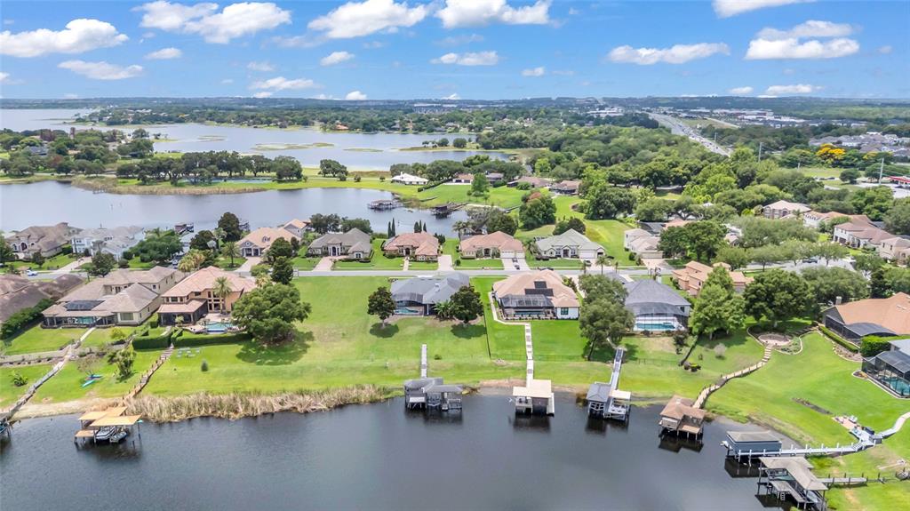 An aerial view of waterfront houses with private docks along a lake under a cloudy sky — 906 JOHNS POINT DRIVE, OAKLAND, FL