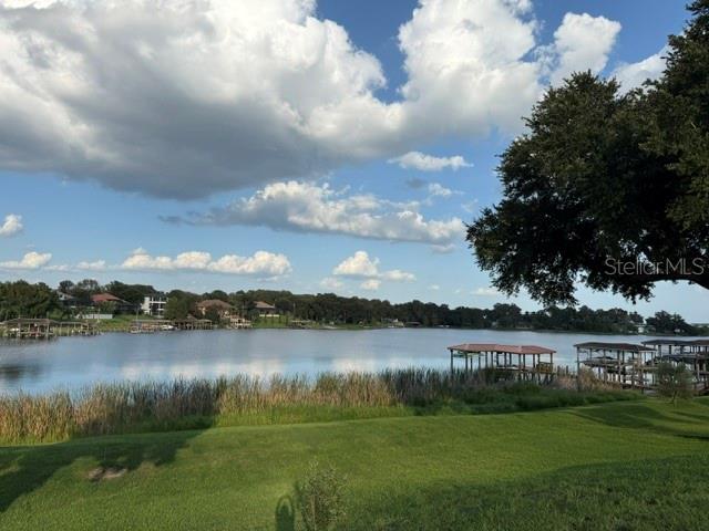 A grassy lawn overlooks a lake with several wooden boat docks under a cloudy sky — 906 JOHNS POINT DRIVE, OAKLAND, FL