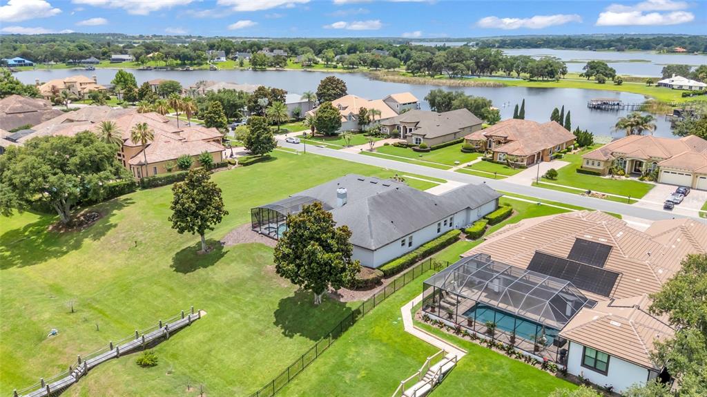 An aerial view shows suburban houses with swimming pools near a large lake — 906 JOHNS POINT DRIVE, OAKLAND, FL