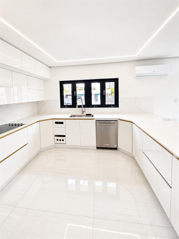 A modern white kitchen features glossy cabinets, stainless steel appliances, and a large window — Santa Teresita 2204 MCLEARY ST, SAN JUAN, PR