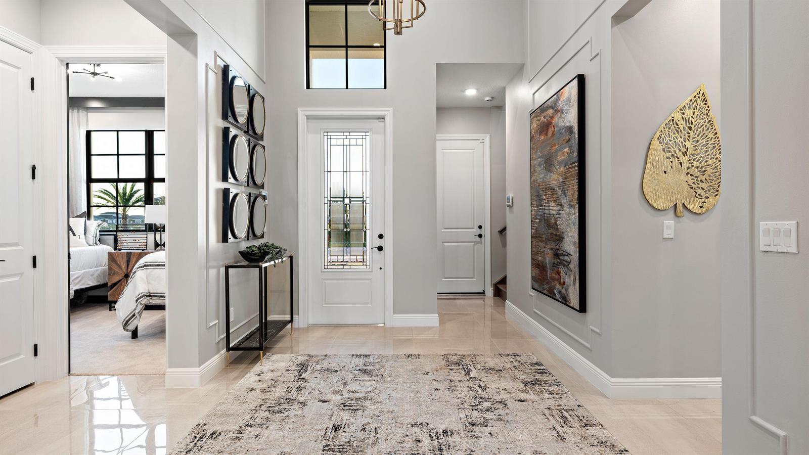 A bright entryway features a patterned rug, a console table, wall art, and a front door — 5627 Saint Armands Way, Westlake FL 33470, WESTLAKE, FL