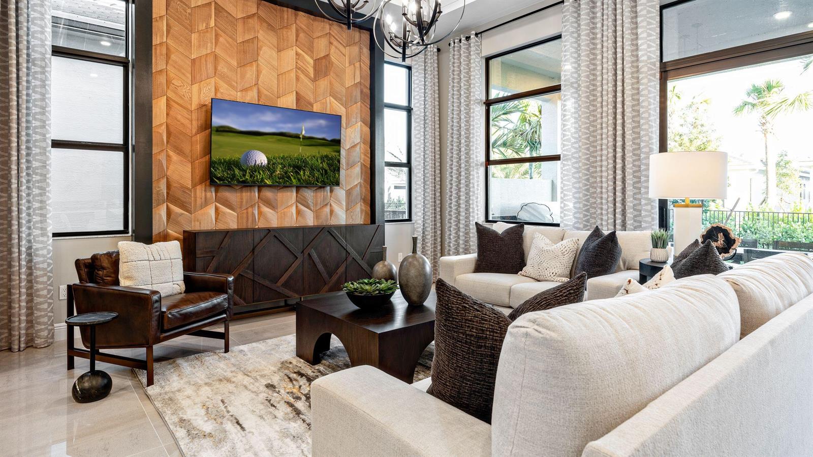 A living room features a wood-paneled accent wall, a television, and neutral-toned furniture — 5627 Saint Armands Way, Westlake FL 33470, WESTLAKE, FL