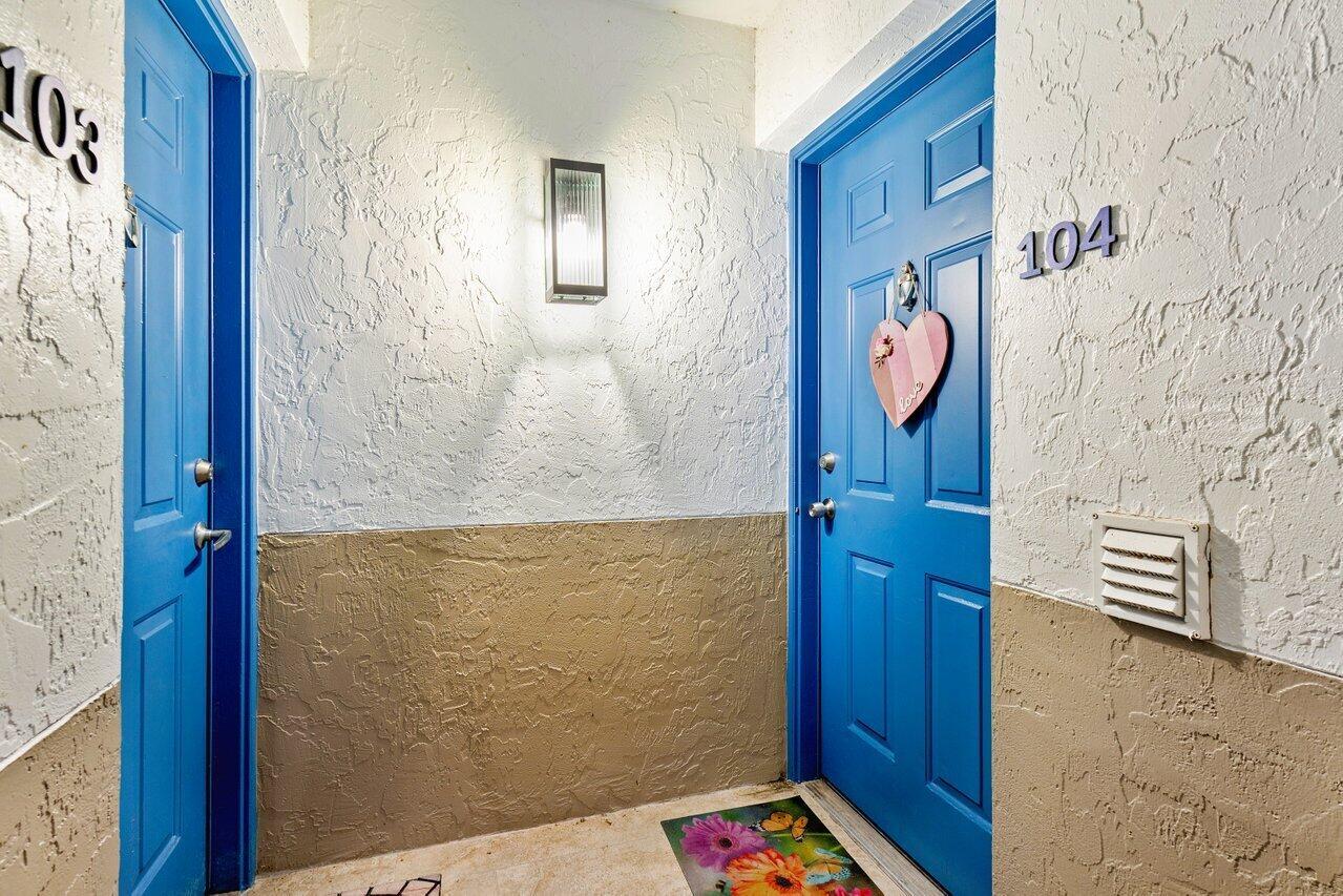 A hallway features two blue apartment doors numbered 103 and 104 with textured walls — 3111 Clint Moore Road, Boca Raton FL 33496, BOCA RATON, FL