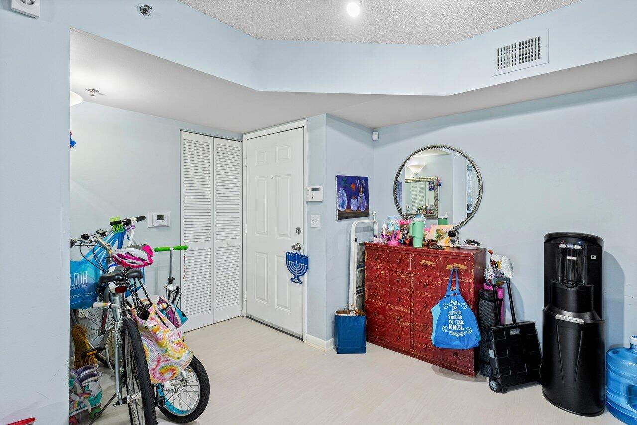An entryway features light blue walls, a red wooden dresser, bicycles, and a white door — 3111 Clint Moore Road, Boca Raton FL 33496, BOCA RATON, FL