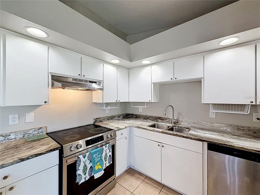A kitchen with white cabinets, stainless steel appliances, and granite countertops — 6311 PINEHURST DRIVE, SPRING HILL, FL