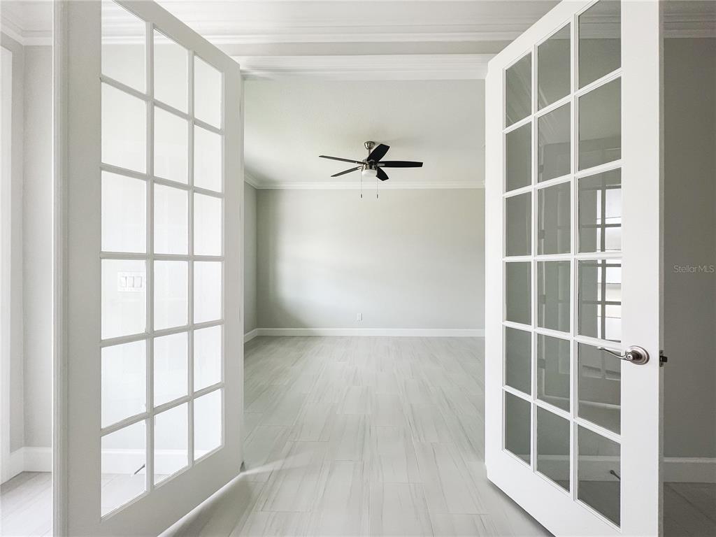 A room with light-colored tile flooring and a ceiling fan viewed through open French doors — 5240 WILLOW LAKE COURT, SARASOTA, FL