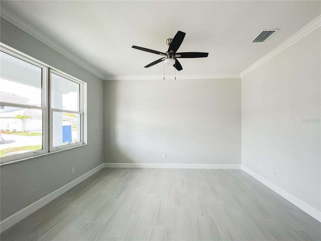 An empty room with light gray walls, wood-look tile flooring, and a ceiling fan — 5240 WILLOW LAKE COURT, SARASOTA, FL