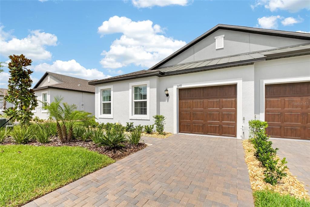 A light-colored house exterior features a brown garage door and a paved driveway — 6693 HOMEBOUND WAY, NEW PORT RICHEY, FL